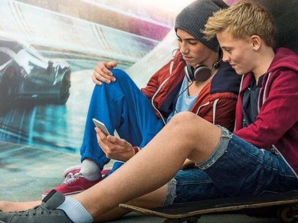 Telekom - Jungen gucken zusammen auf ein Smartphone als Investitionsbeispiel für das Recht auf Meinungsfreiheit, Information, Privatsphäre | Kinder Perspektivenfonds